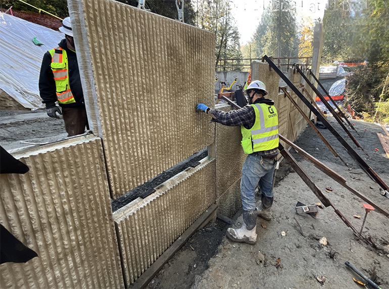 Crews place structural earth wall panels along the edges of the bridge approach. 