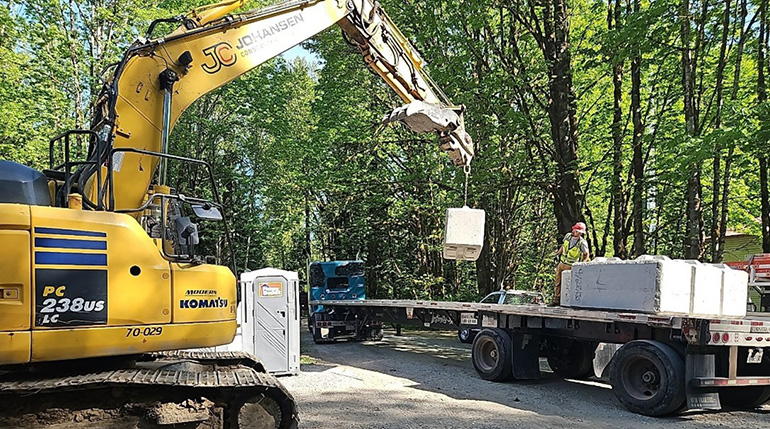 Construction crane removes concrete blocks from flatbed