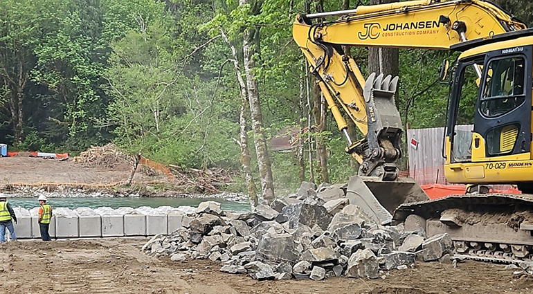 Maintenance workers and heavy machinery along river
