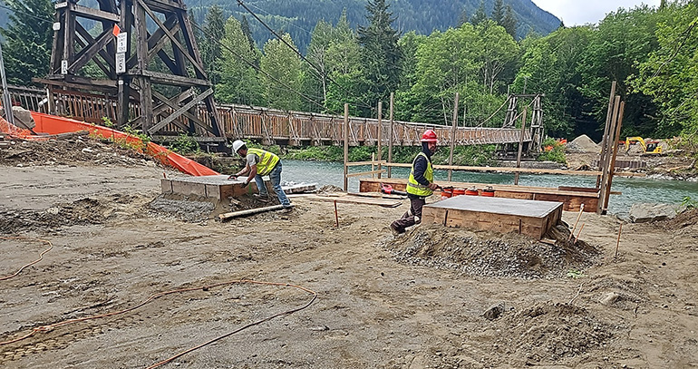 Maintenance workers pouting and finishing concrete on riverbank