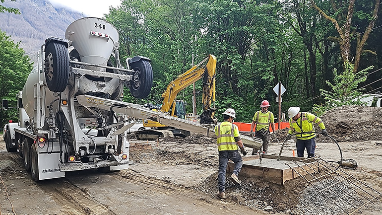 Concrete truck and workers pouring concrete