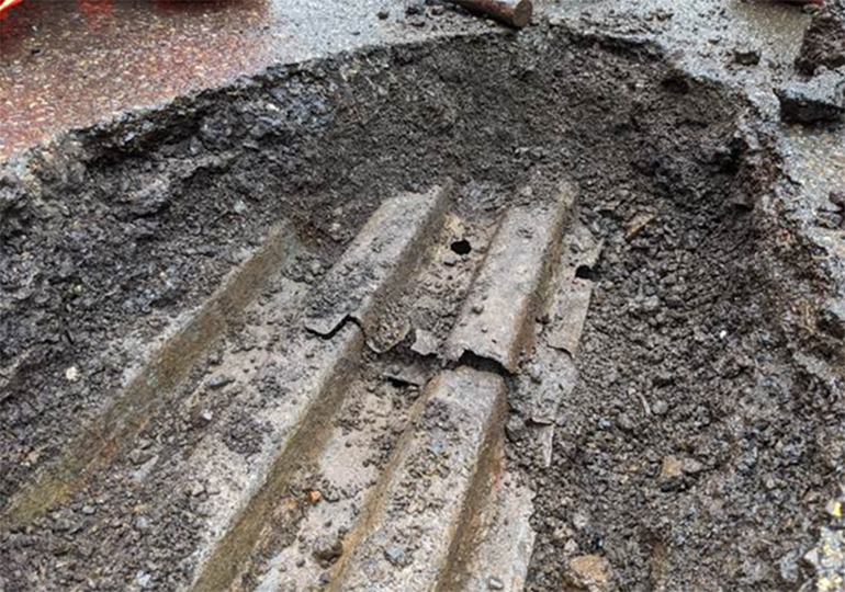 A close-up look at  a damaged bridge deck, rusted and sinking.