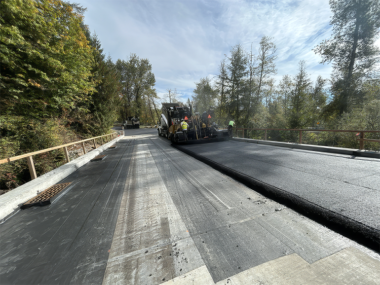 Crew paving a road under construction with fresh asphalt