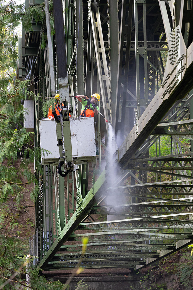 King County crew members pressure washing a bridge.