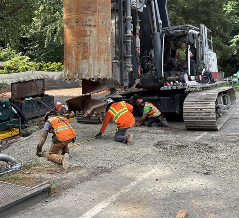 Construction workers preparing heavy machine drill
