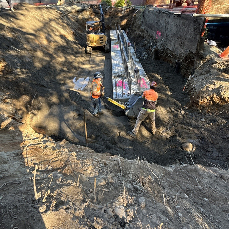 Workers putting gravel in trench
