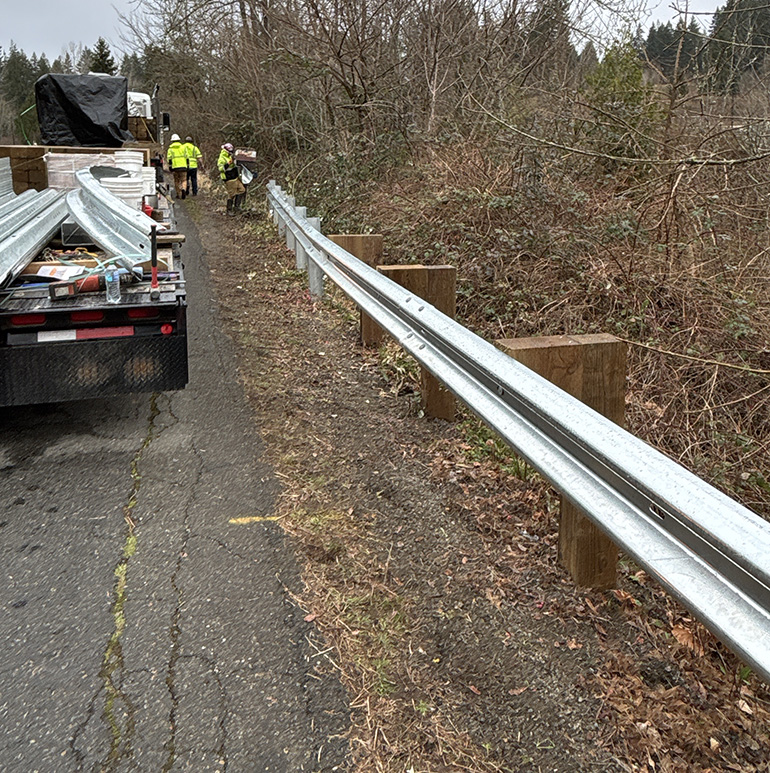 Work crews installing guardrail on roadside