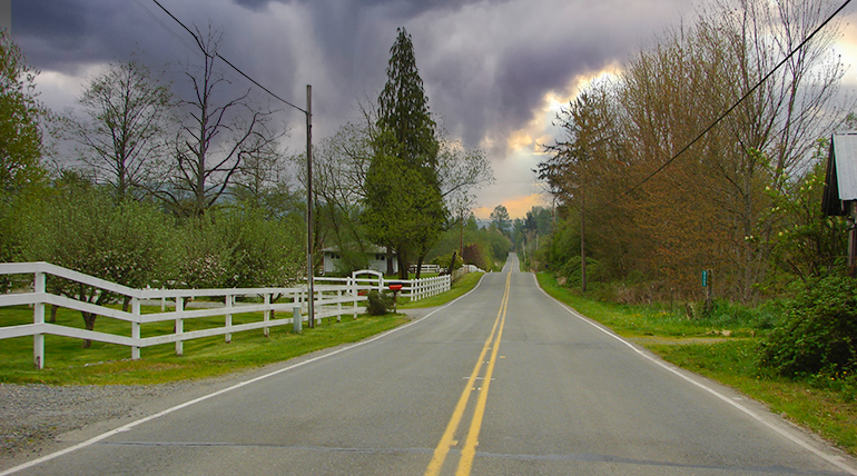 Laned road with white fence on side.