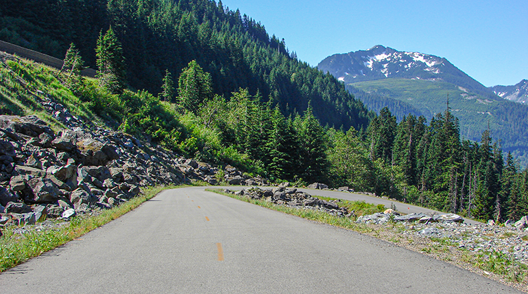 Road winding downhill with mountains on the horizon