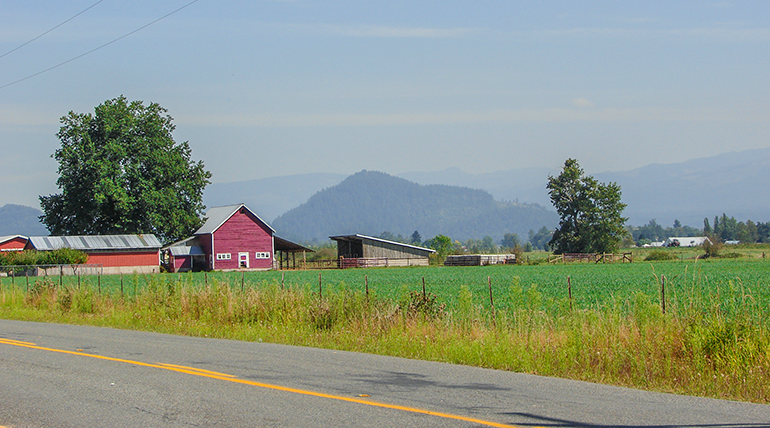 Road passing in front of Red barn and farm house.