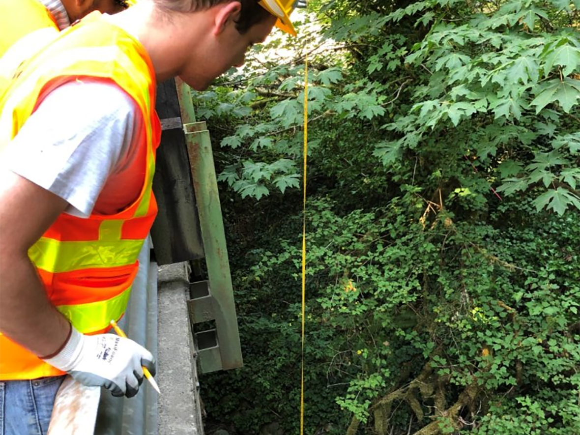 Interns measure the height of a bridge.