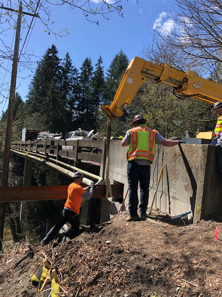 Crews installing a temporary steel beam to support the bridge deck 