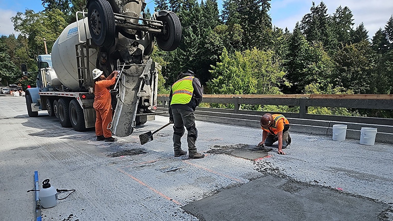 Crew members on bridge patching with concrete