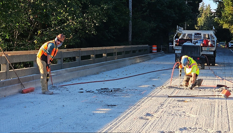 Worker on bridge deck removing damage