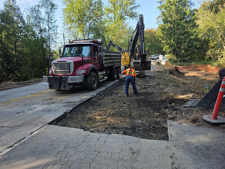 Crew member shoveling gravel next to Mack truck