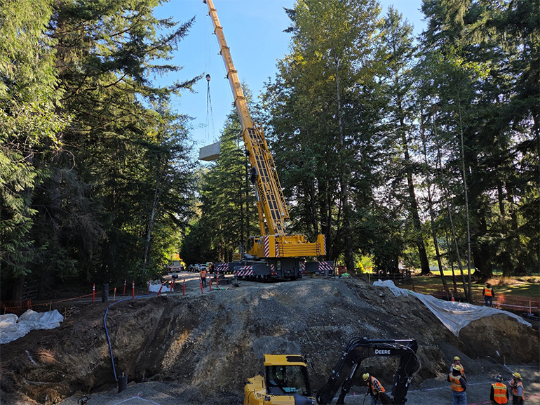 Crane lowering large concrete slabs on job site
