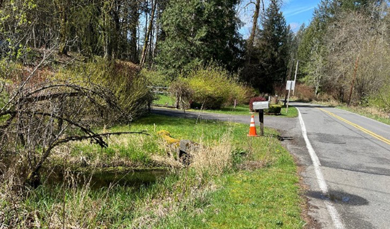 Street location of an old three-and-a-half-foot corrugated metal pipe under the road .
