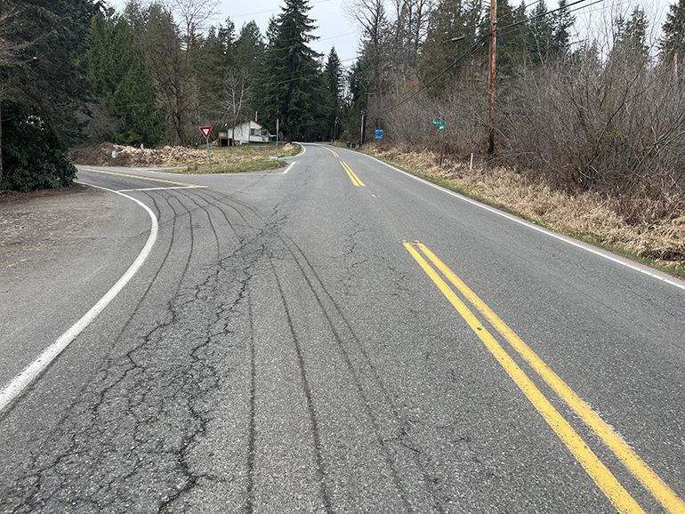 Cracked and potholed concrete road with yellow and white striping