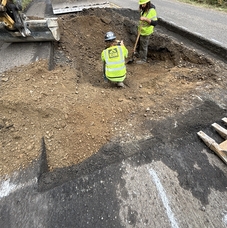 Two crew workers with shovels working in ditch in road