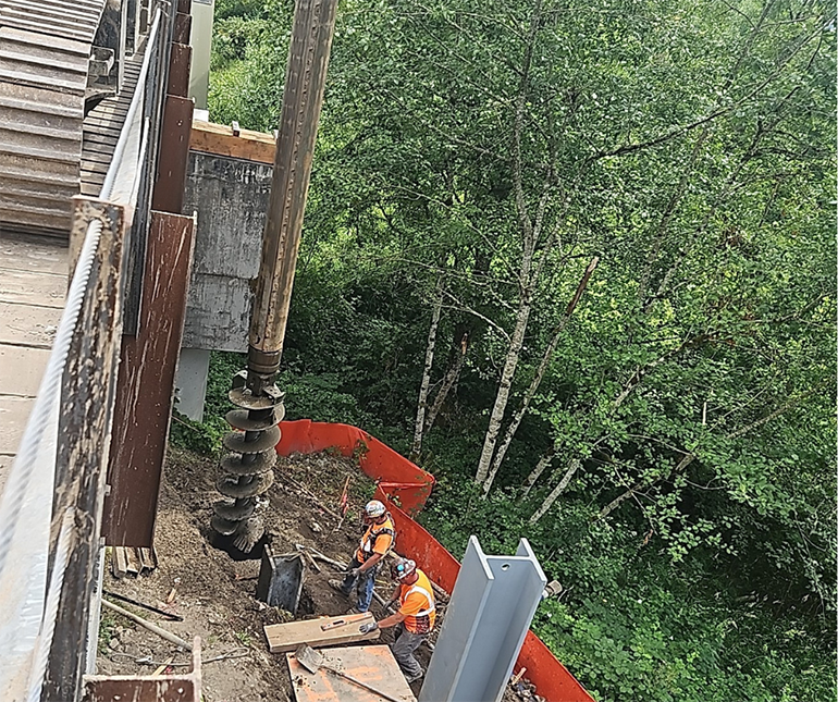 A large drill, called an auger, drills into the soil below the bridge on NE Tolt Hill Rd to prepare for the new steel soldier piles. 