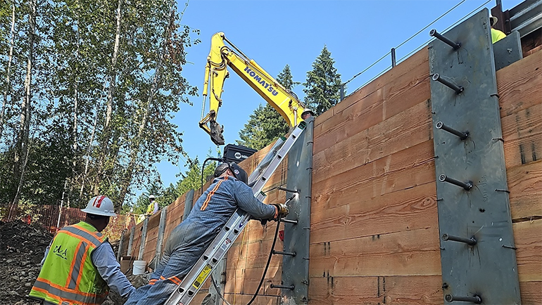 Workers weld studs into soldier piles.