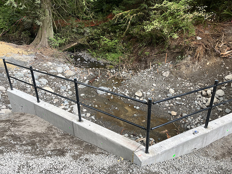 New box culvert shows the safety guardrail with the creek flowing freely below it.