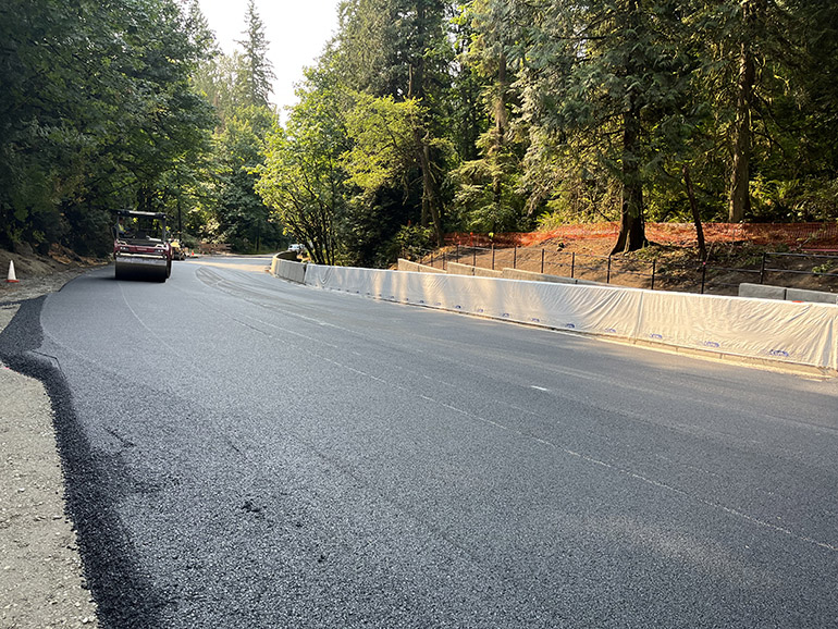 Crews roll over the smooth surface of the freshly paved section of NE Woodinville Duvall Road above the new concrete box culvert. 