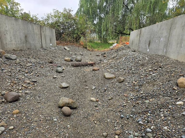 Natural materials such as gravel, rocks, and logs are added to the interior of the box culvert.