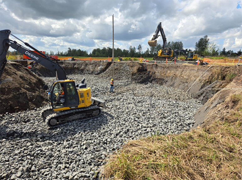 Rocks used to create culvert base are placed with large equipment.