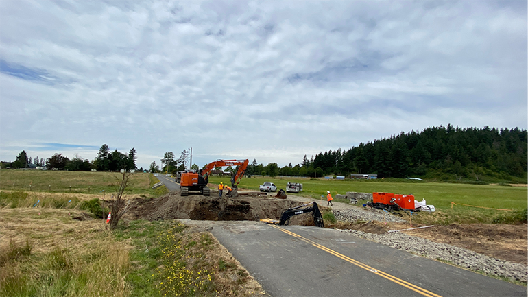 Using heavy machinery, crews dig into the ground to remove an old, rusted pipe and make space for a much larger concrete box culvert. 