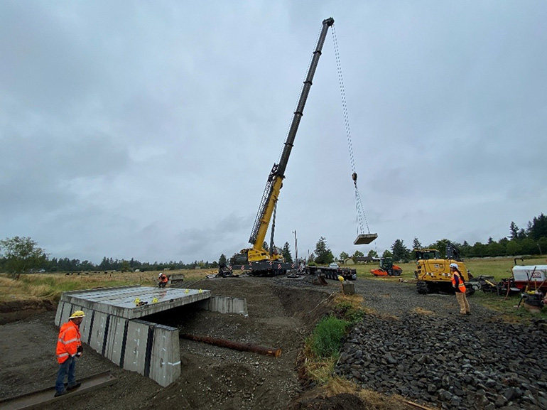 A large crane moves pieces of the lid into place.