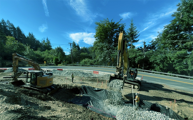 Maintenance crew workers use heavy machinery to spread broken rock.