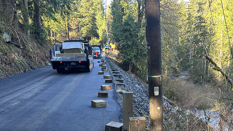 New asphalt on road with roads maintenance vehicles.