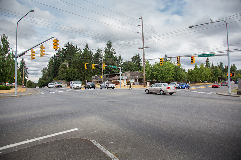 Four way intersection of SE Petrovitsky Road with cars and pedestrians.
