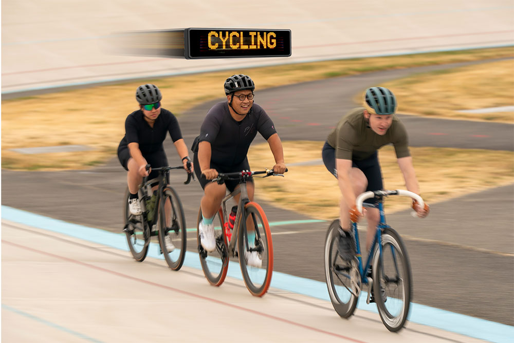 A group of cyclists race along a velodrome with large wooden curved walls around them.