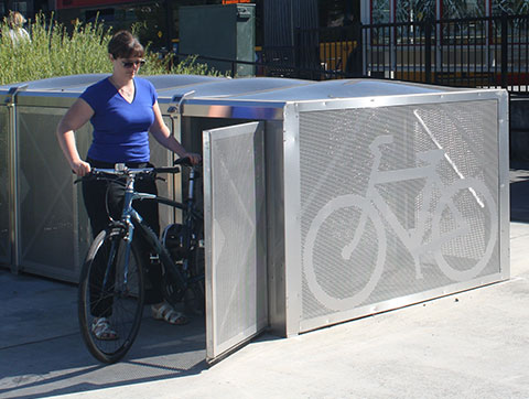 Woman placing a bike into an outdoor bike locker