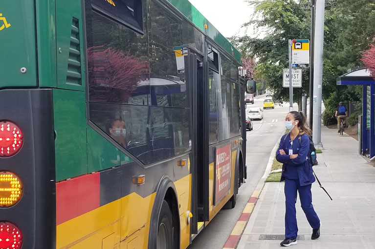 Masked rider safely boarding the bus