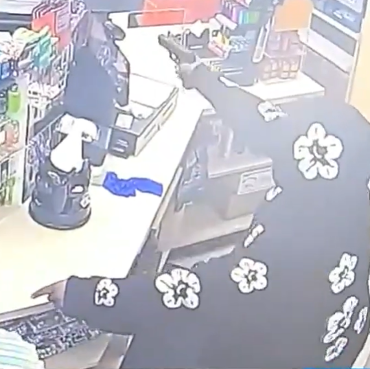 Picture of robber pointing gun at gas station clerk