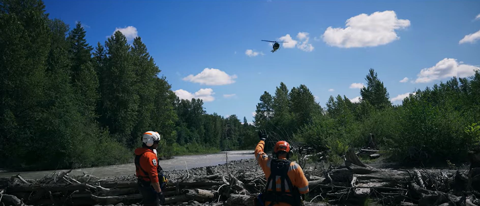Helicopter returns to pick up rescue workers by side of the river