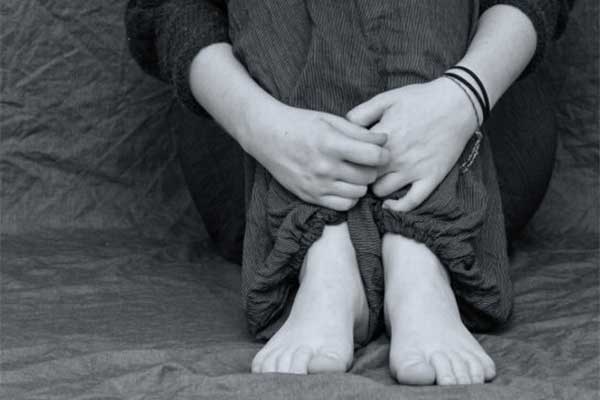 Image of woman sitting, arms wrapped around legs