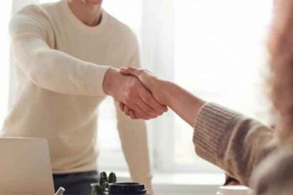 Two people shaking hands across a desk