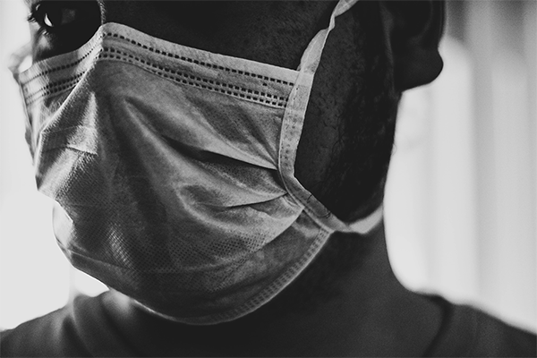 Close crop black and white image of person wearing a medical mask