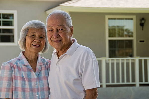 Senior couple standing in front of house