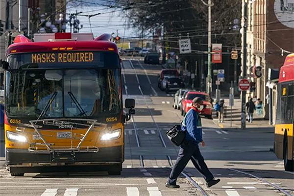 Person crossing street in front of Metro Transit bus