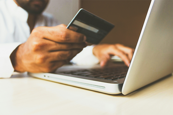 Image of person holding credit card while making a purchase on a laptop